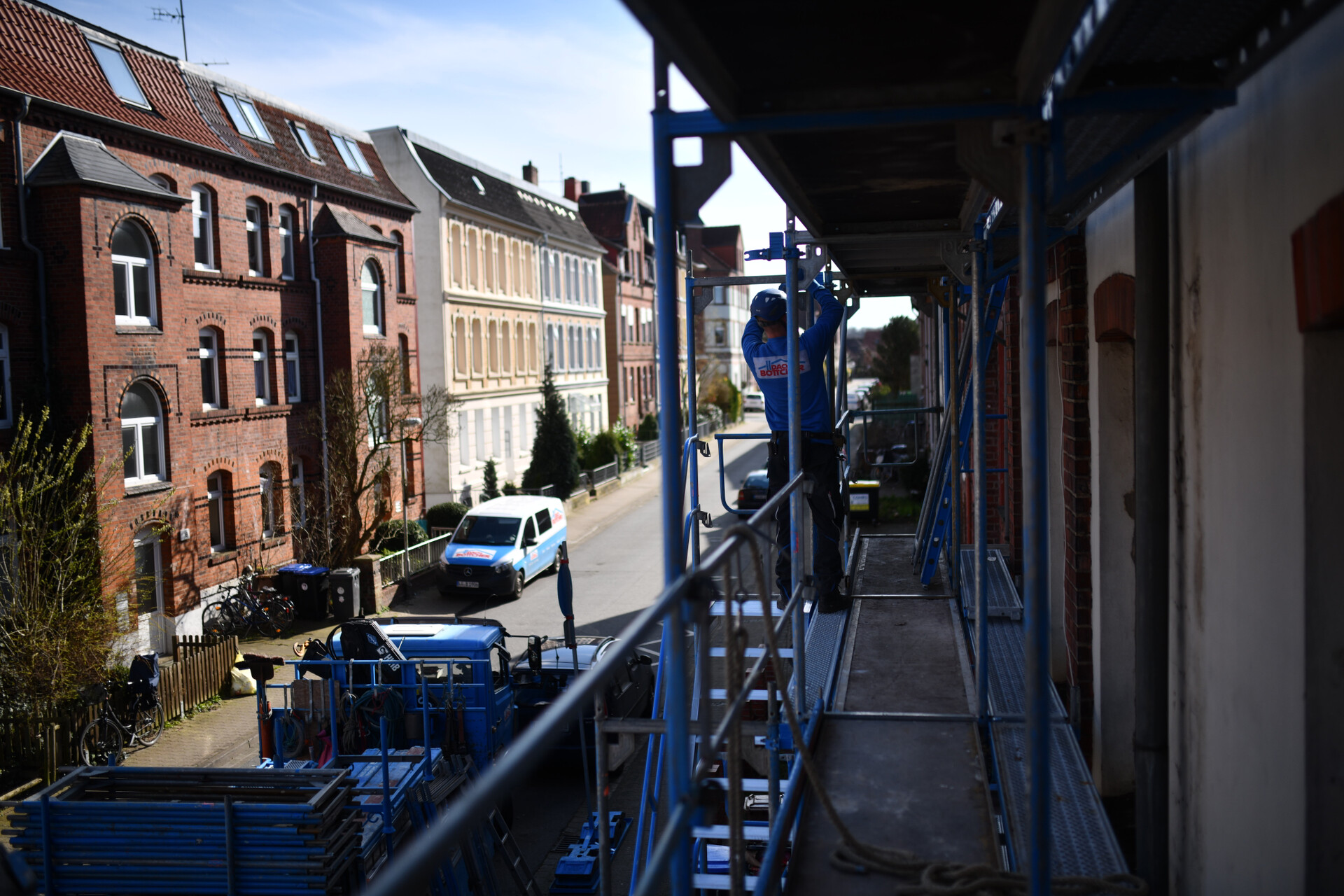 Chris baut Gerüst. Setzt Wandanker am Treppenturm. scaffolding germany. Rückenansicht mit Logo.